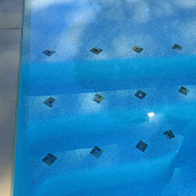 Pool Interior With Blue Plaster Finish And Dark Tile Accents Arranged In Rows