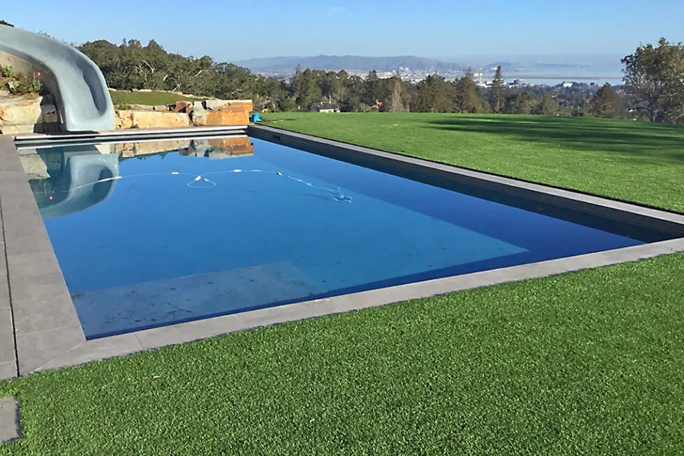Modern Rectangular Pool With Blue Tile Finish And Waterfall Feature Overlooking Bay And Hills