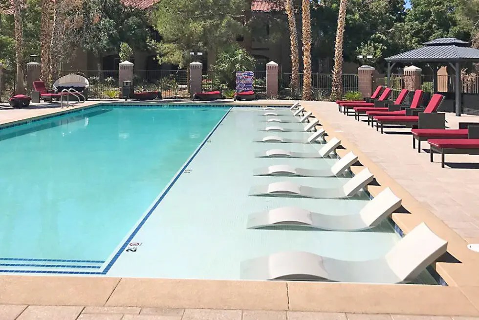 Resort-Style Lap Pool With Lounge Chairs And Shaded Cabanas Surrounded By Mature Trees