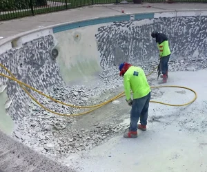 Pool Remodeling Crew Using Hydroblasting To Remove Old Plaster And Tile From Pool Walls During Renovation